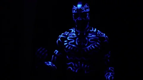 A crazy black man in neon patterns on the body dances and laughs in the dark Stockbeeldmateriaal 82324101