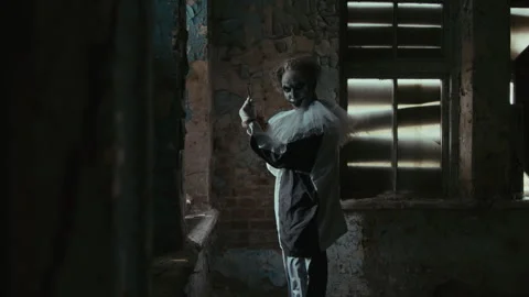 Crazy Clown with Scissors Going to Viewer in Abandoned Building Stock Footage 250939017