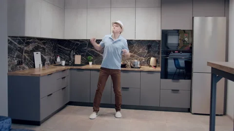 Crazy dance of a man with a hat in front of the kitchen Stock Footage 166127222