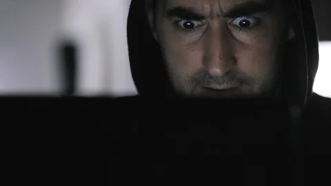 Crazy funny hacker in hood working on a computer at dark room at home Stock Footage 112228810