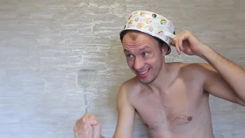 Crazy guy with a pan on his head and a kitchen item in his hands. Stock Footage 136933533