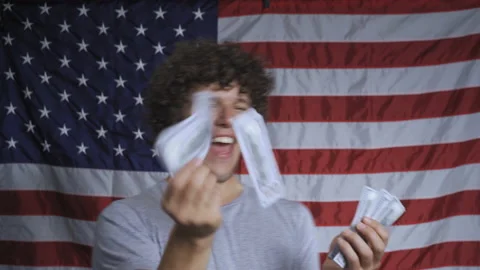 Crazy, happy man throws American dollars against the background of the American Video stock 142647946
