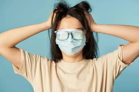 Crazy lady posing in studio with antivirus mask and glasses, holding her head Stock Photos