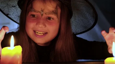 Crazy little witch reading spells at Halloween night by candlelight. School play Video stock 214223373