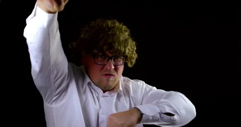 Crazy man with curly wig is waving hands with different emotions at black Видео 116761633