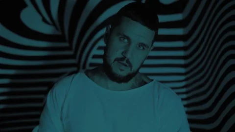 Crazy man in a straitjacket in a psychedelic room looks at you Stock Footage 126002189