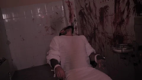 Crazy man in straitjacket tied to a chair, killer psychopath in a room with 스톡 동영상 126001273