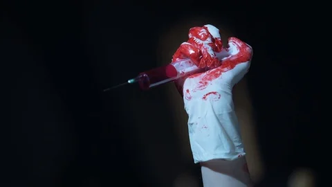 Crazy murderer holding syringe with dripping blood and enjoying terrible view Stock Footage