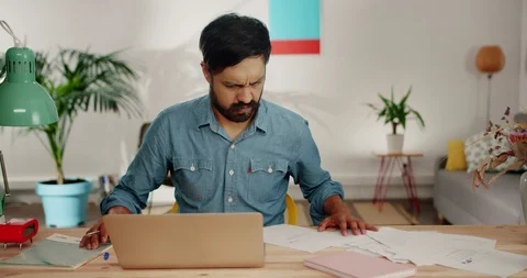 Crazy nervous Hispanic man solving stressful job problems writing on papers in Stock Footage 120744946