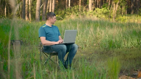Crazy programmer working on laptop in summer forest Stock Footage 154376296