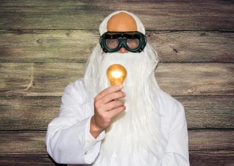 Crazy scientist elderly man holding an inexplicably lit bulb with some strang Stock Photos