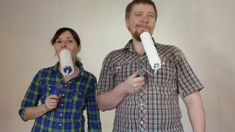 Crazy young couple doing repairs in the room, painting the wall with rollers Stock Footage 74874438