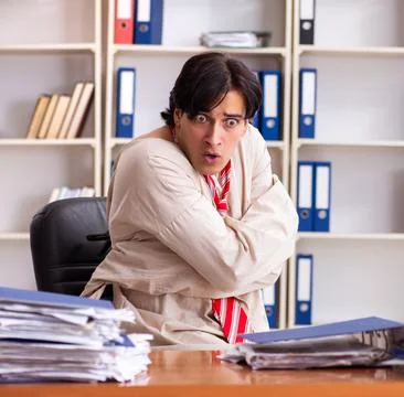Crazy young man in straitjacket at the office Stock Photos