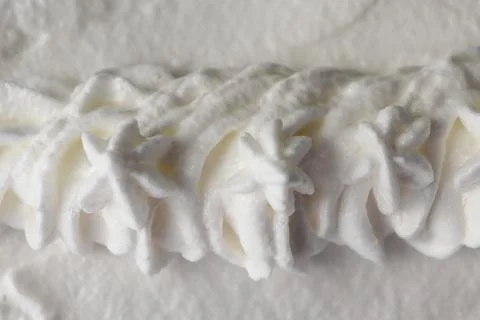 Cream being piped into a decorative shape on a flat surface in a kitchen during Stock Photos