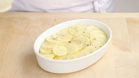 Cream being poured over potato slices in a baking dish Stock Footage 24657705