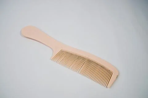 A cream colored comb on a white background. Stock Photos