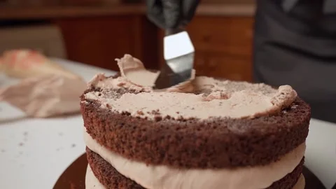 The cream is distributed on the cake with a spatula Stock Footage 153772214