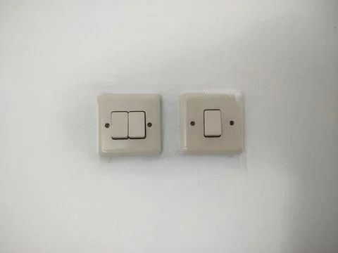 Cream Double and Single Light Switches Mounted Side by Side on a White Wall Stock Photos