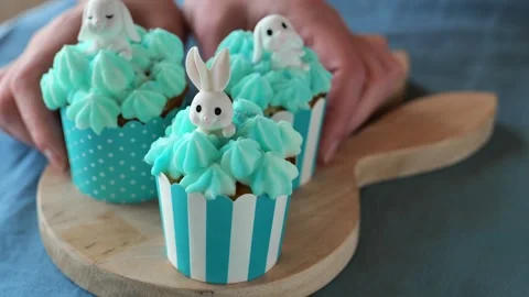 Cream easter cupcakes with white rabbits on a wooden tray Stock Footage 299030689