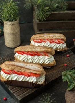 Cream eclairs with strawberries on the table Stock Photos