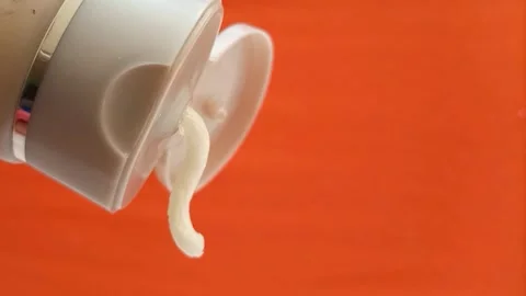 Cream face wash texture squeezed out of a tube on an orange background, closeup. Stock Footage 320861207