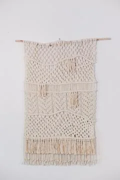 Cream macrame decor displayed hanging on a wall. Stock Photos