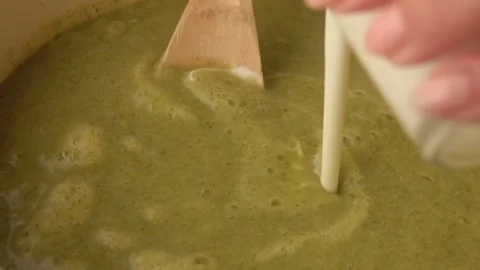 Cream is poured into a pan with broccoli spoon Stock Footage 233845245
