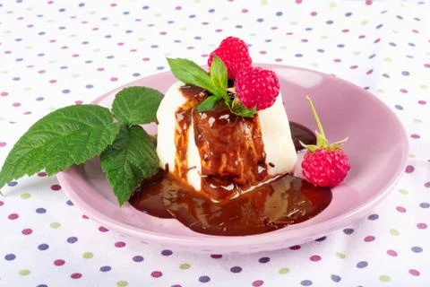 Cream pudding with chocolate sauce, raspberry and mint on  tablecloth Stock Photos