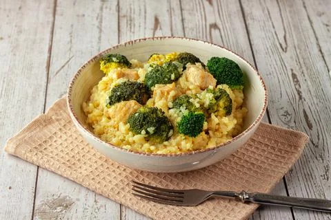 Creamy risotto with chicken and broccoli on wooden background Stock Photos