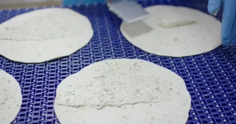 Creamy spread applied to round flatbread with a spatula, Food Factory Stock Footage 340033530
