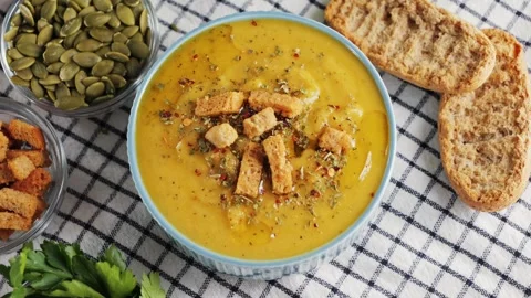 Creamy vegetable soup with bread, pumpkin seeds, herbs and croutons. Video stock 326199521