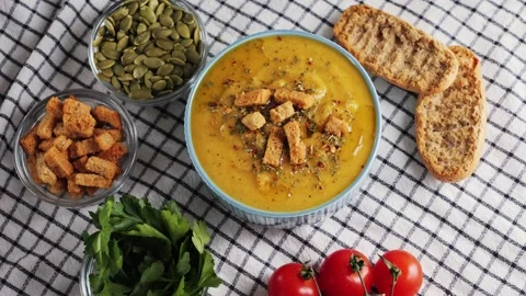 Creamy vegetable soup with bread, pumpkin seeds, herbs and croutons. Video stock 329279190