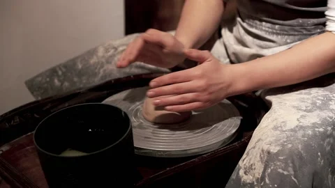 Create of ceramic bowl on a turntable. Young lady in black apron Stock Footage 201568438