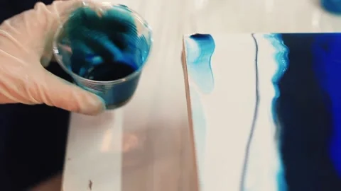 To create pattern on surface using liquid dyes. Gloved hand holds wooden stick. Stock Footage 145333792