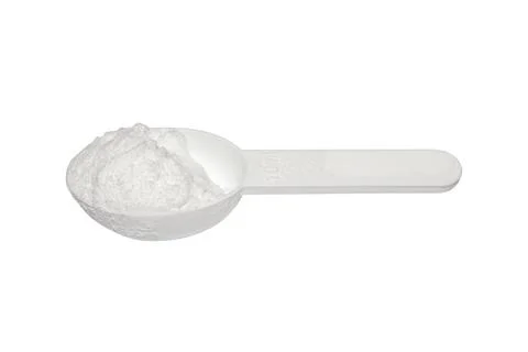 Creatine in a measuring plastic spoon on a white background. Stock Photos