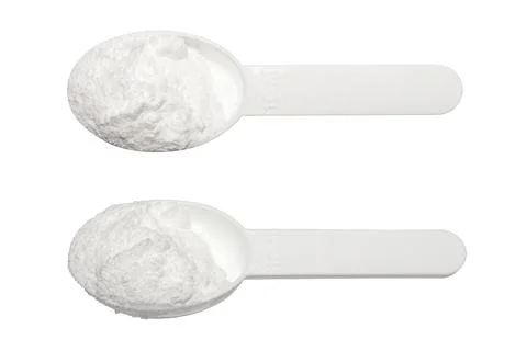 Creatine in a measuring plastic spoon on a white background. Stock Photos