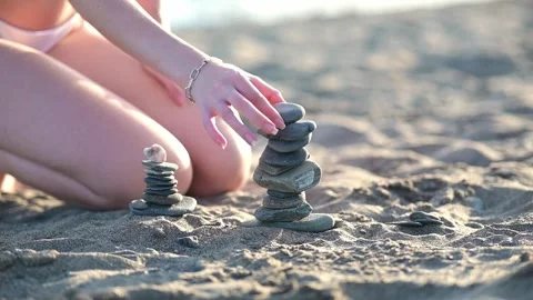 Creating balanced stone towers on a sandy beach Video stock 289768671