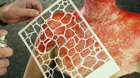 Creating body art with the help of a stencil and spray slow motion closeup Stock Footage 74351323