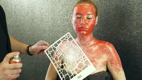 Creating body art with the help of a stencil and spray slow motion Stock Footage 74351703