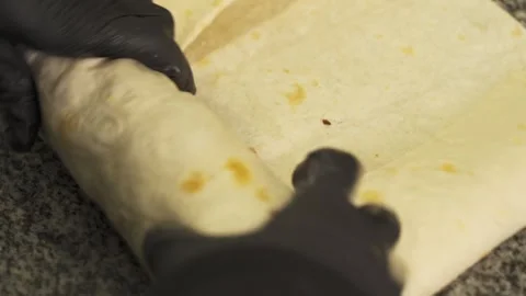 Creating delicious shawarma rolls with expert precision in the kitchen Stock Footage 324459715