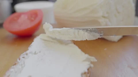 Creating delicious snack with fresh tomato and creamy spread on warm bread Stock Footage 340551089