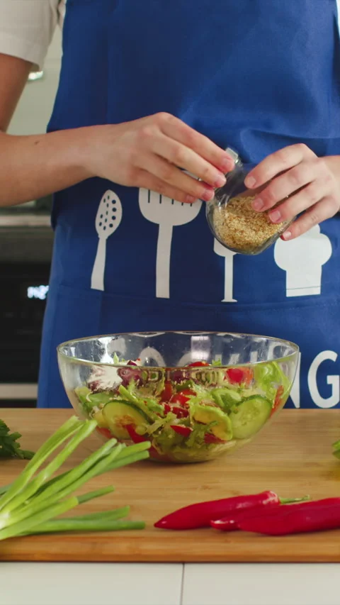 Creating a fresh and vibrant salad in a bright kitchen space Stock Footage 341763380