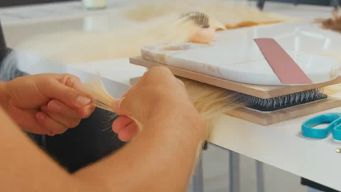 Creating hair extensions at a crafting table in a bright workspace Stock Footage 333000658
