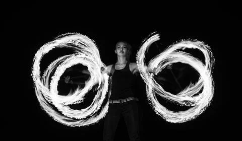 Creating incredible patterns of fire. Sexy woman roll dragon staff in darkness Fotos de archivo