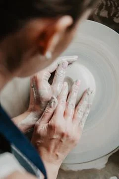 Creating a jar or vase of white clay close-up. Woman hands making clay jug. Stock Photos