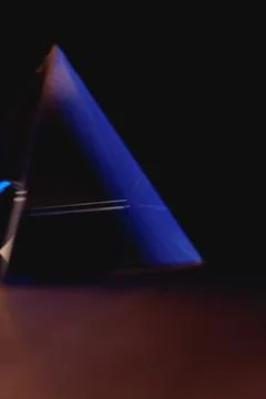 Creating light and shadow with a glass prismatic pyramid in dark surroundings Photos