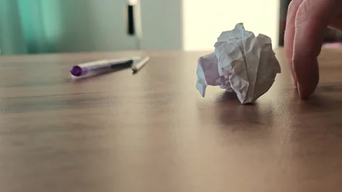 Creating a paper ball and rolling it across a table while using a pen as a guide Stock Footage 345090021