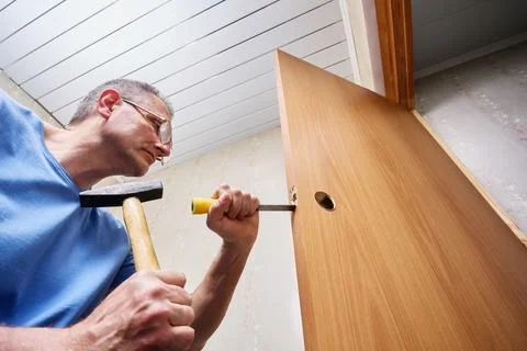 Creating precise mortise with chisel and hammer, installer shapes cavity in.. Stock Photos