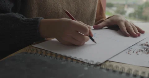 Creating simple sketches on white paper with a red pencil. Artistic desk setup Stock Footage 301617548