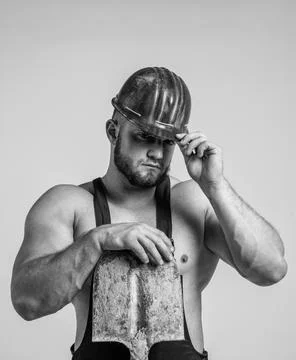 Creating solid foundation. athletic builder in helmet. sexy man with shovel 库存照片